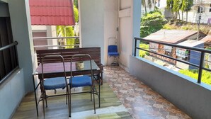 A balcony with a table and chairs, a mop, and a red awning. - Hotel O Aida Lestari (Sebulu)