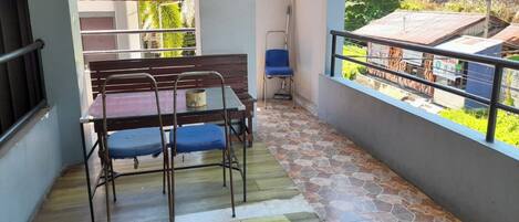 A balcony with a table and chairs, a mop, and a red awning.