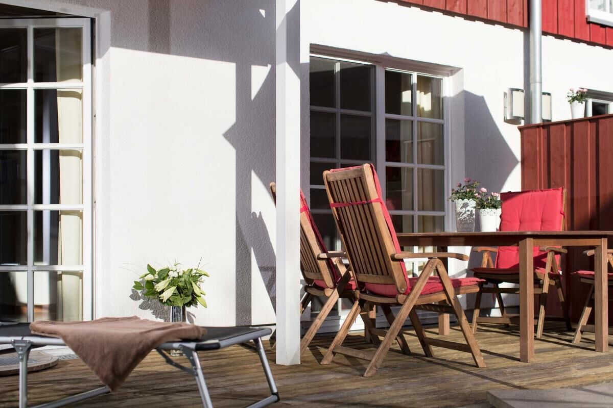 Un patio al aire libre con una mesa y sillas de madera, una silla plegable y una planta en maceta.