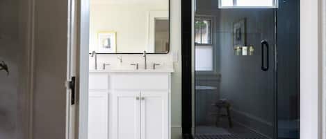 A bathroom with a white vanity, a large mirror, and a glass shower enclosure.