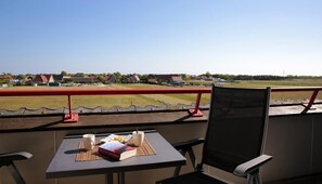 Enjoy a quiet morning on the balcony with a table set for two, featuring a book, a mug, and a pastry.