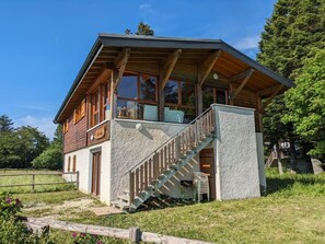 Une cabane en bois dotée d’un balcon, d’un escalier et d’un petit espace porche.