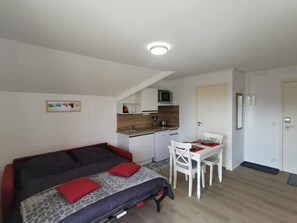 A compact room with a bed, a small kitchenette, and a dining area. - Studio 2 pers. avec accès piscine et sauna (Les Deserts)
