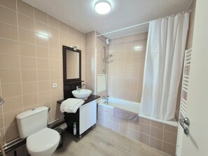 A bathroom with a toilet, sink, mirror, shower, and bathtub. - Studio 2 pers. avec accès piscine et sauna (Les Deserts)