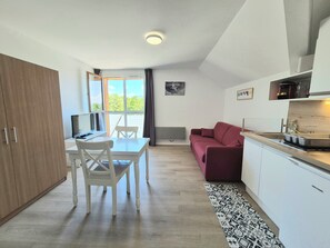 Una cocina compacta con una mesa de comedor, sillas, un sofá rojo y vistas al exterior.