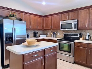 A modern kitchen with wooden cabinets, stainless steel appliances, and a white countertop. - Value Rate! Check out this pool! Disney! 588 (Davenport)