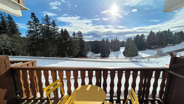 Ein Balkon mit Blick auf eine verschneite Landschaft und Bäume.