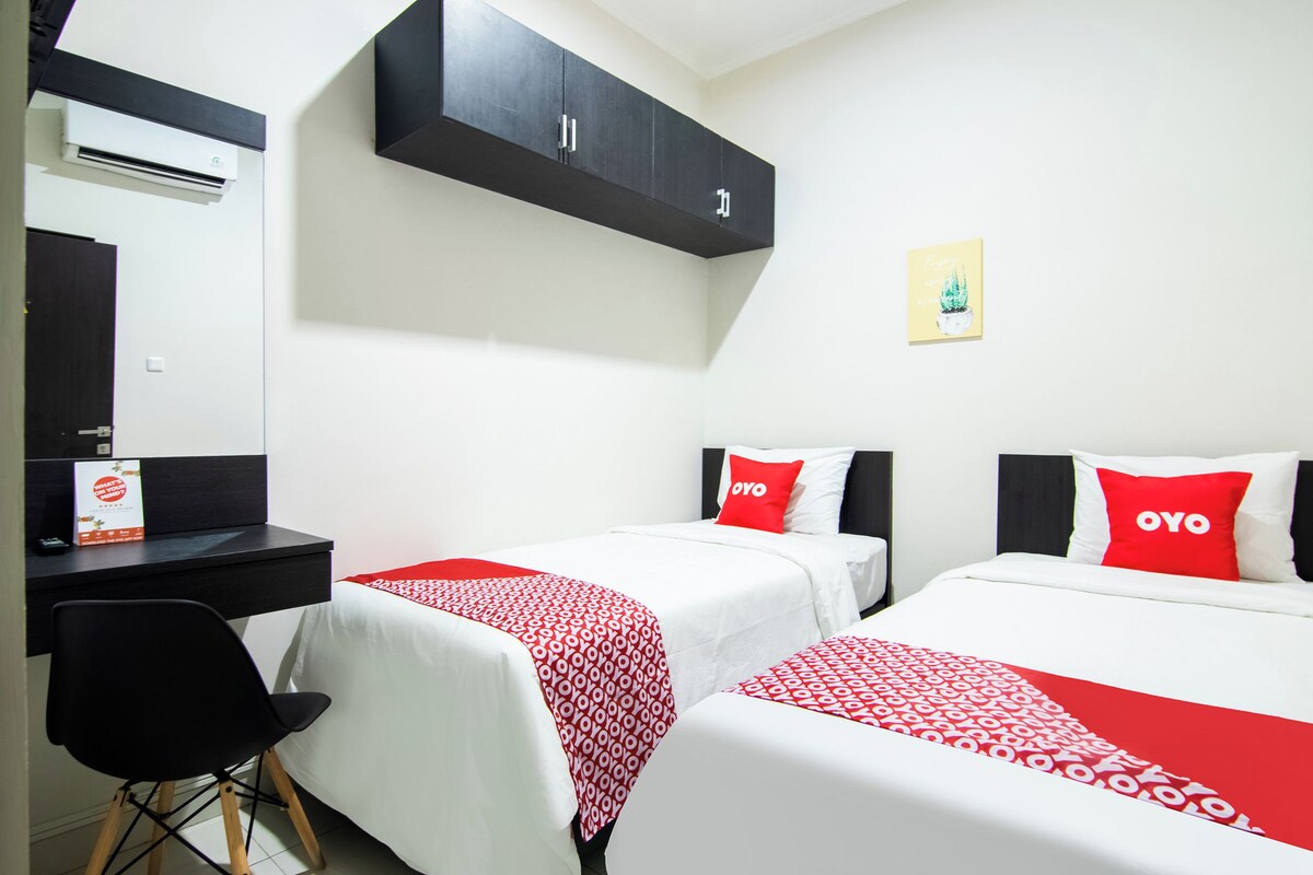 Una habitación de hotel con dos camas, un escritorio y un armario.