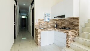 A modern kitchen with a built-in island, white cabinetry, and a wood-patterned backsplash. - OYO 3826 Columbus Residence K11 (Karawang)