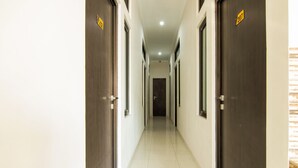 A long, narrow hallway with doors on both sides, leading to a dark room at the end. - OYO 3826 Columbus Residence K11 (Karawang)