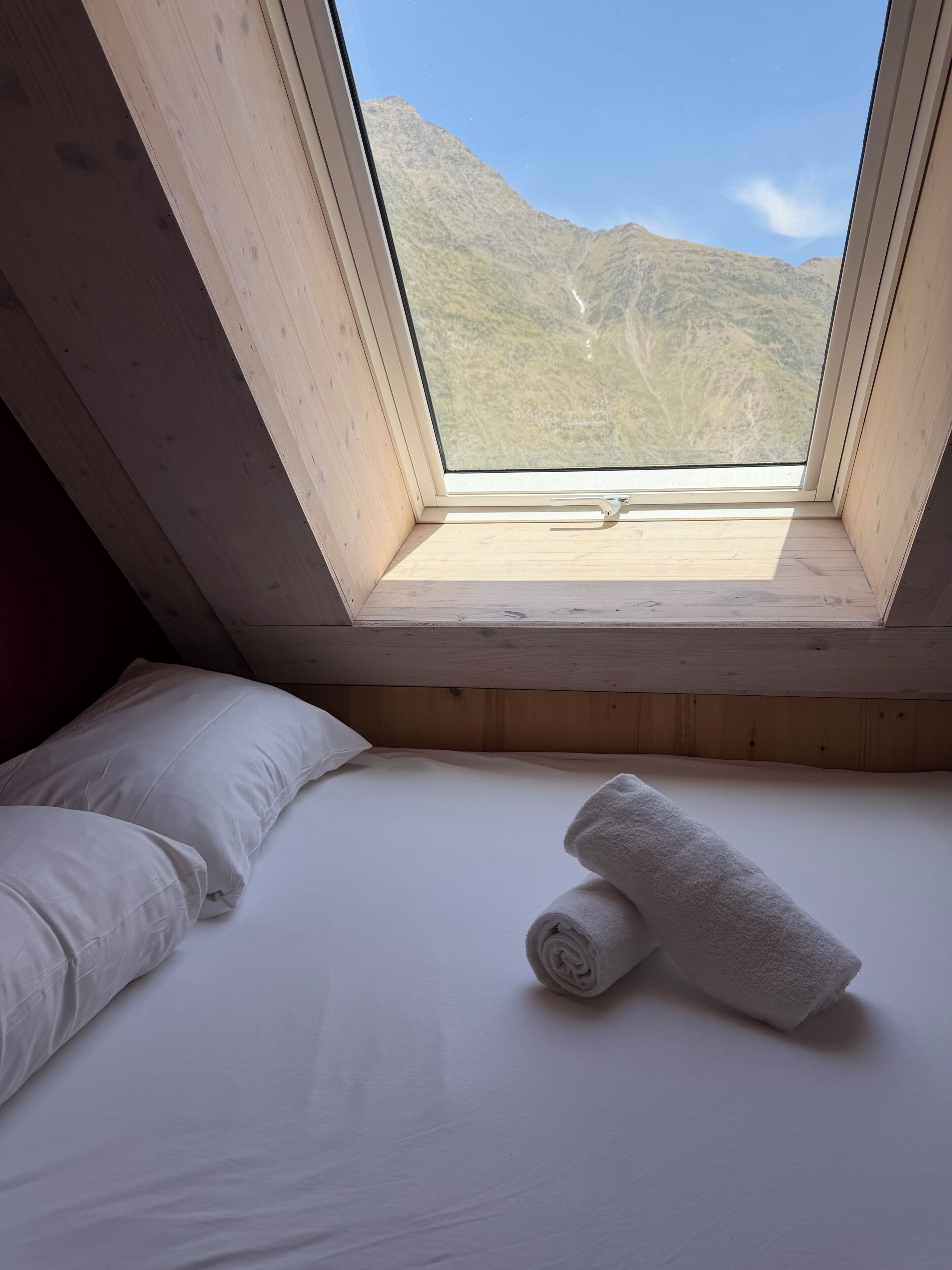 Une chambre avec un lit, une fenêtre et une vue sur les montagnes.