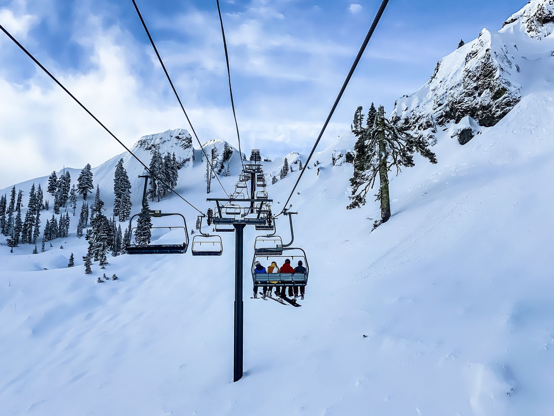 Eine Seilbahn mit Fahrgästen, umgeben von schneebedeckten Bäumen und Bergen.