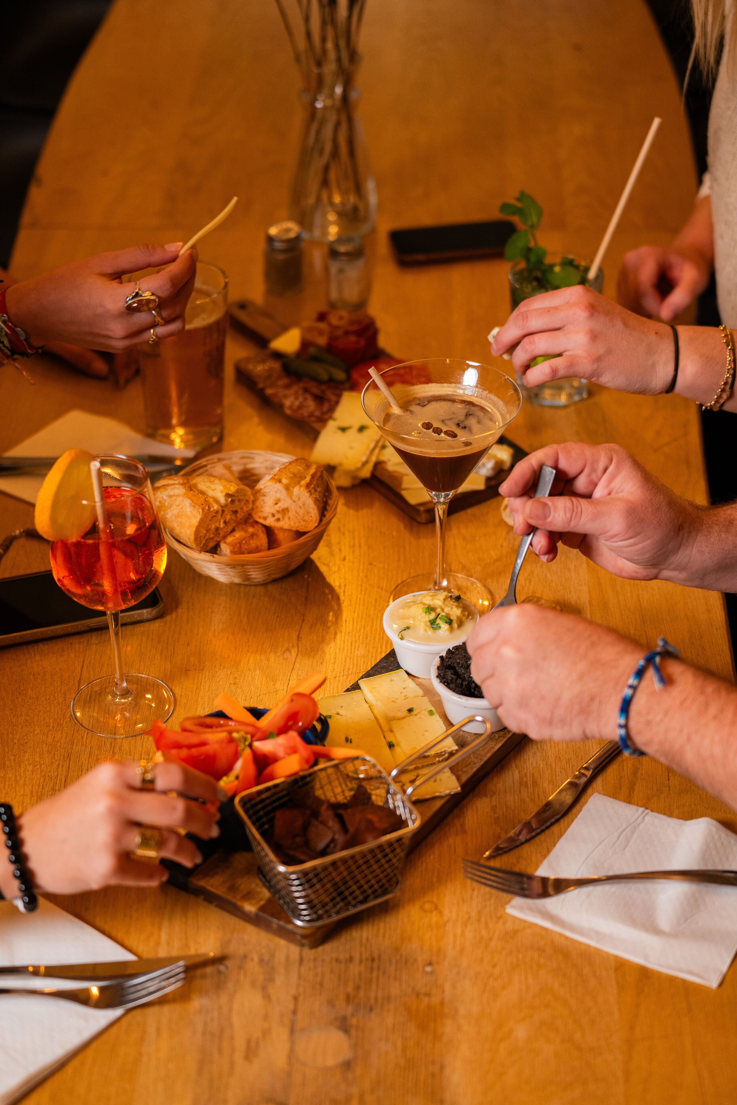 A wooden table with various food items, glasses, and utensils.