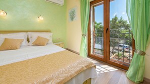 Un dormitorio con cama, mesita de noche y ventana con cortinas verdes.