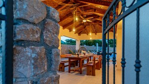 Comedor rústico con paredes de piedra, muebles de madera e iluminación colgante.