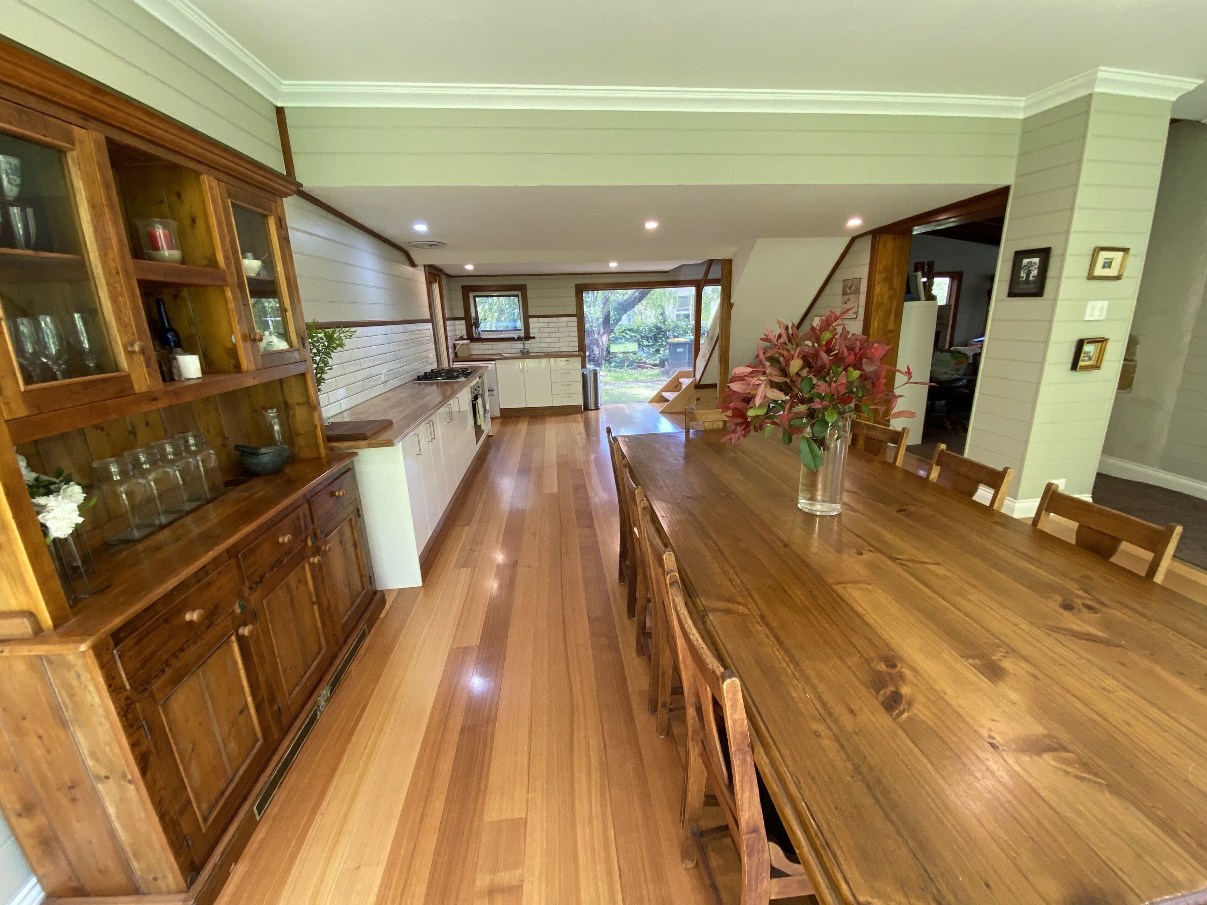 A spacious kitchen with wooden cabinets, a long dining table, and a view of the outdoors.