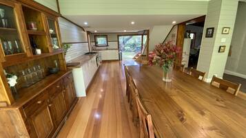 A spacious kitchen with wooden cabinets, a long dining table, and a view of the outdoors.