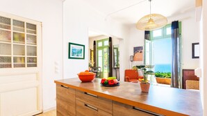 A modern kitchen with a wooden countertop, a bowl of fruit, and a potted plant.