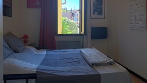 Une chambre à coucher avec un lit, une fenêtre, un radiateur et des éléments décoratifs sur les murs.