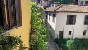 Une ruelle étroite, bordée de bâtiments, avec un mur jaune sur le côté gauche et un bâtiment blanc sur le côté droit.