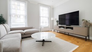 A modern living room with a sofa, a coffee table, a TV, and a plant.