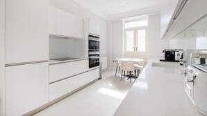 A modern kitchen with white cabinetry, a central island, and a dining area with chairs.