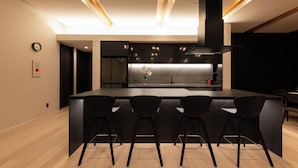 A modern kitchen with a central island, black bar stools, and a clock on the wall. - Yuki Sugi at Intuition (Kutchan)