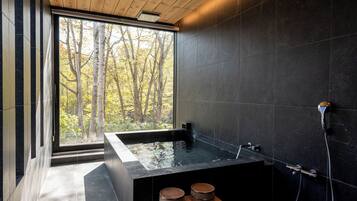 Relax in a serene space with a large bathtub and forest views through a large window.