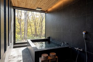 A modern bathroom with a large bathtub, wooden accents, and a view of trees through a large window. - Yuki Sugi at Intuition (Kutchan)