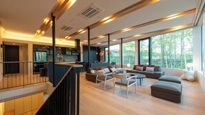 A modern living space with a staircase, a dining area, and a large window offering a view of trees. - Yuki Sugi at Intuition (Kutchan)
