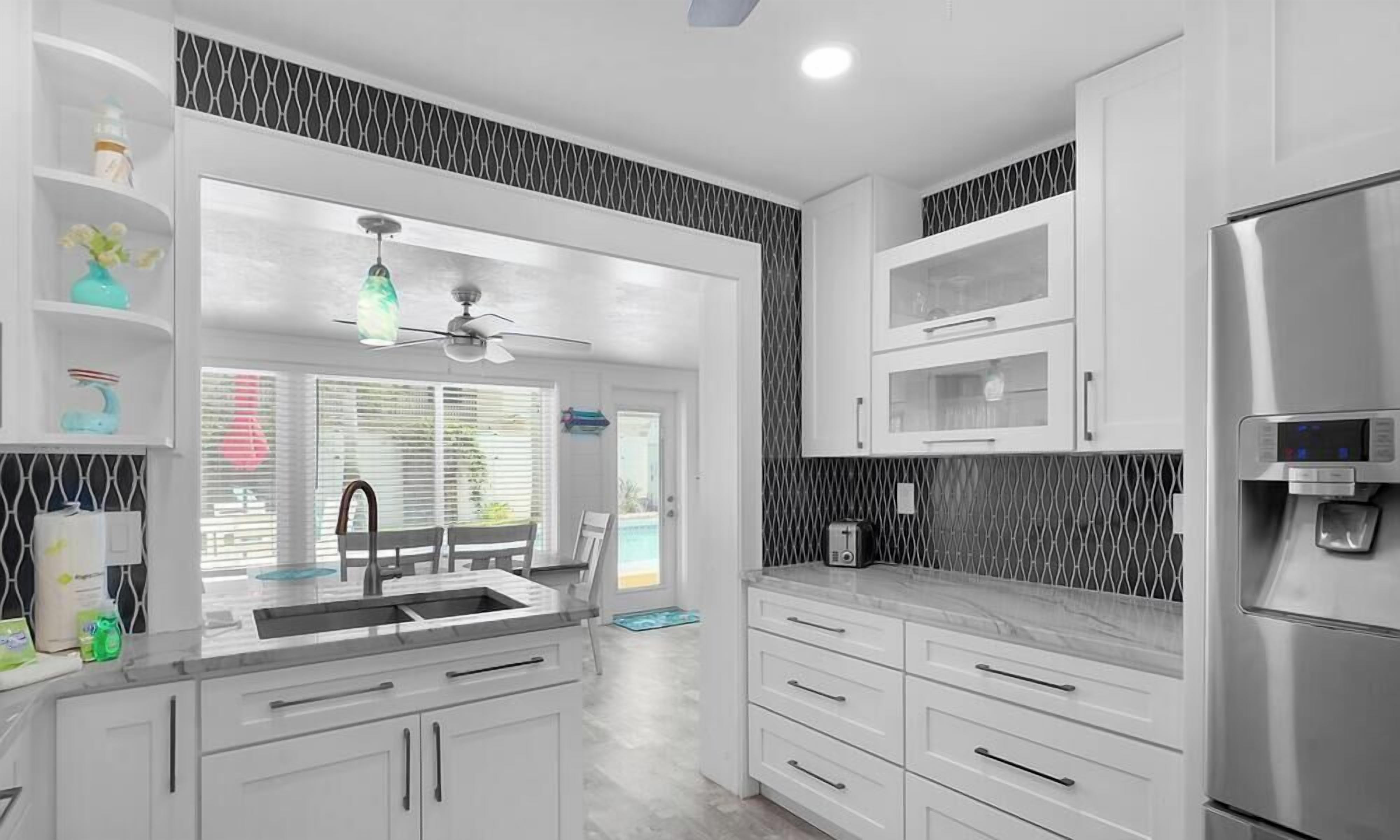 A modern kitchen with white cabinets, a stainless steel refrigerator, and a built-in water dispenser.