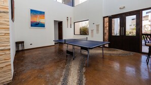 Amplia habitación con mesa de ping pong, un cuadro y vistas al exterior.