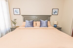 A neatly made bed with a headboard, two bedside tables, and a lamp.