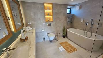 A modern bathroom with a bathtub, a sink, and a toilet. There are shelves with decorative items and a mirror.