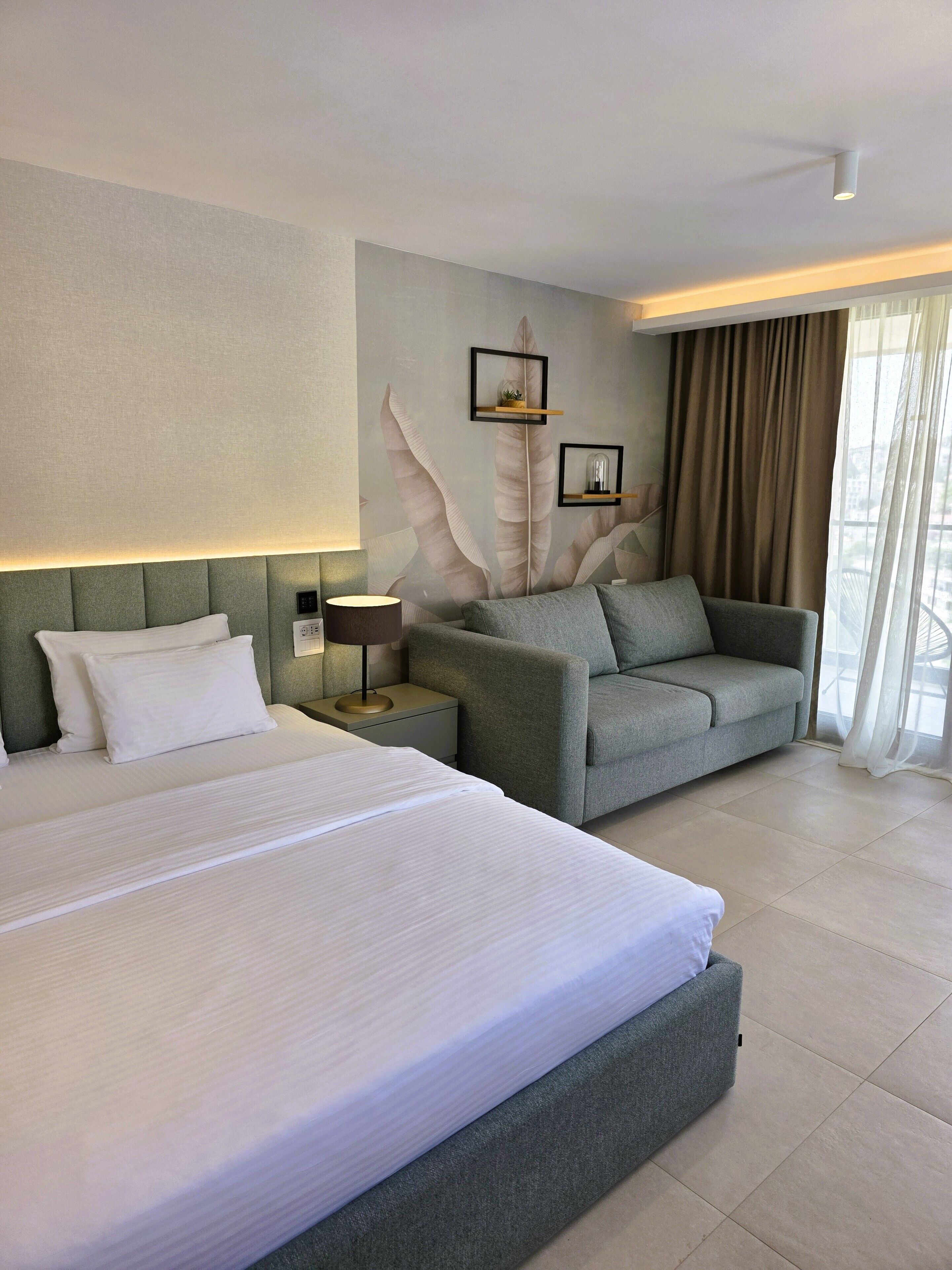 A hotel room with a large bed, a sofa, a nightstand, and a wall with a feather design.