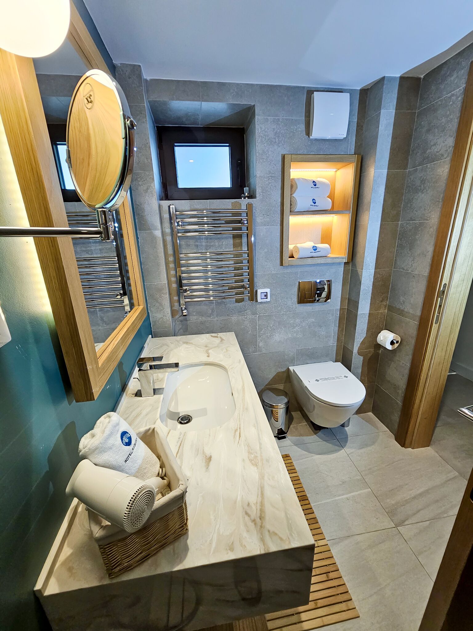 Un baño moderno con un espejo grande, un lavamanos empotrado, un inodoro y un calentador de toallas.