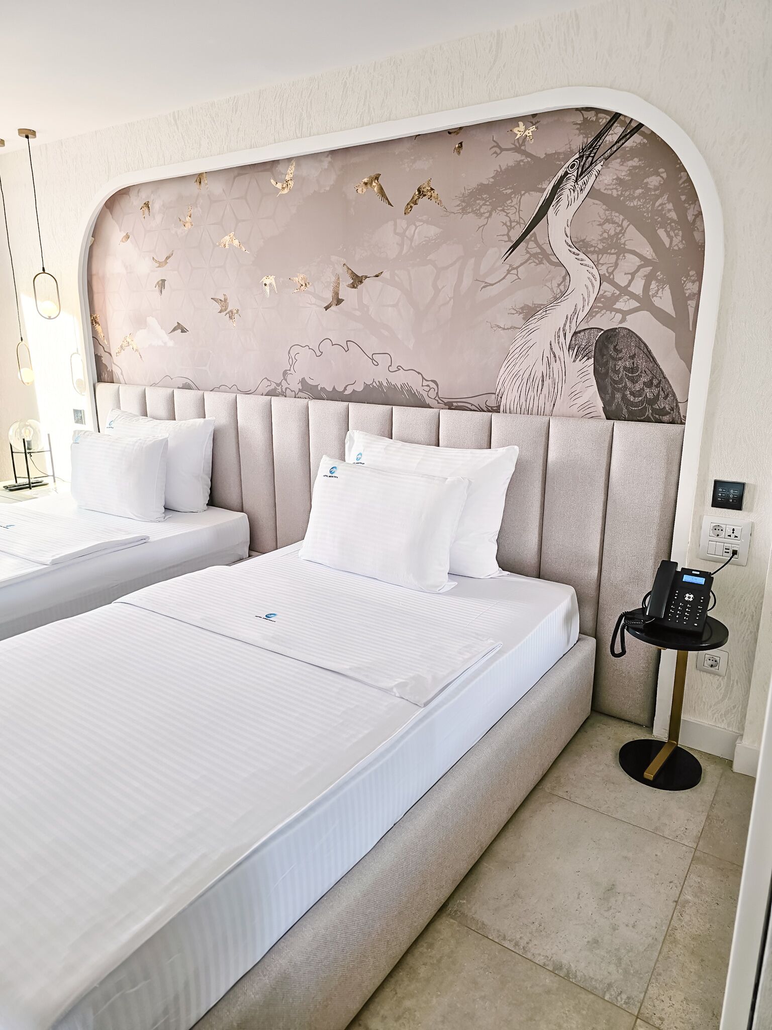 A hotel room with two beds, a wall mural, and a bedside phone.