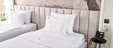 A hotel room with two beds, a wall mural, and a bedside phone.