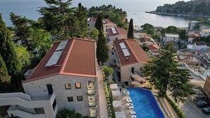 A residential area with a swimming pool, multiple buildings, and a view of the sea.