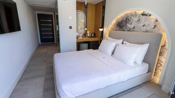 A modern hotel room with a large bed, a vanity with a mirror, and a unique wall design.