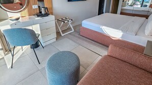 A modern hotel room with a bed, a desk with a chair, a TV, and a large window.