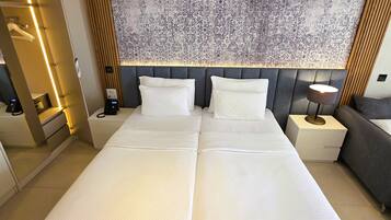 A double bed with a grey headboard, bedside tables with lamps, and a patterned wall behind.