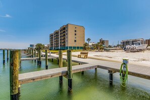A waterfront hotel with a dock, beach, and a building with multiple floors.