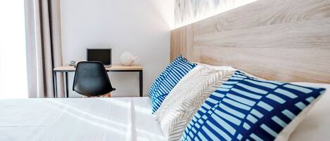 A hotel room with a bed, a desk, a chair, and a wall with a textured design.