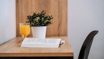 Une table en bois avec un verre de jus d’orange, une plante en pot et un menu ouvert.