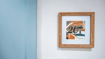 Obra de arte abstracta enmarcada con el número '207' sobre una pared blanca.