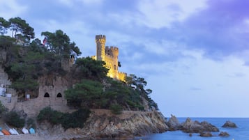 Un castillo costero con una playa en primer plano.