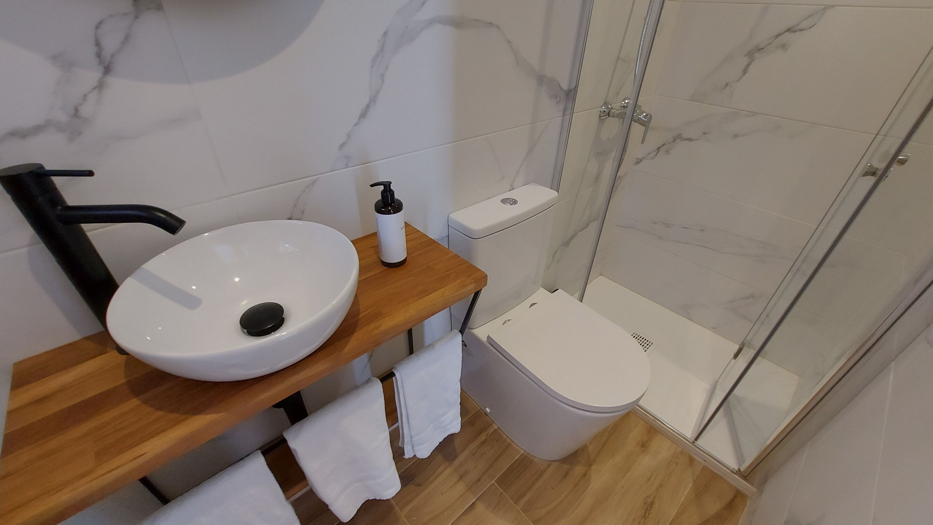 Une salle de bain avec un lavabo, des toilettes et une douche, le tout de couleur blanche.