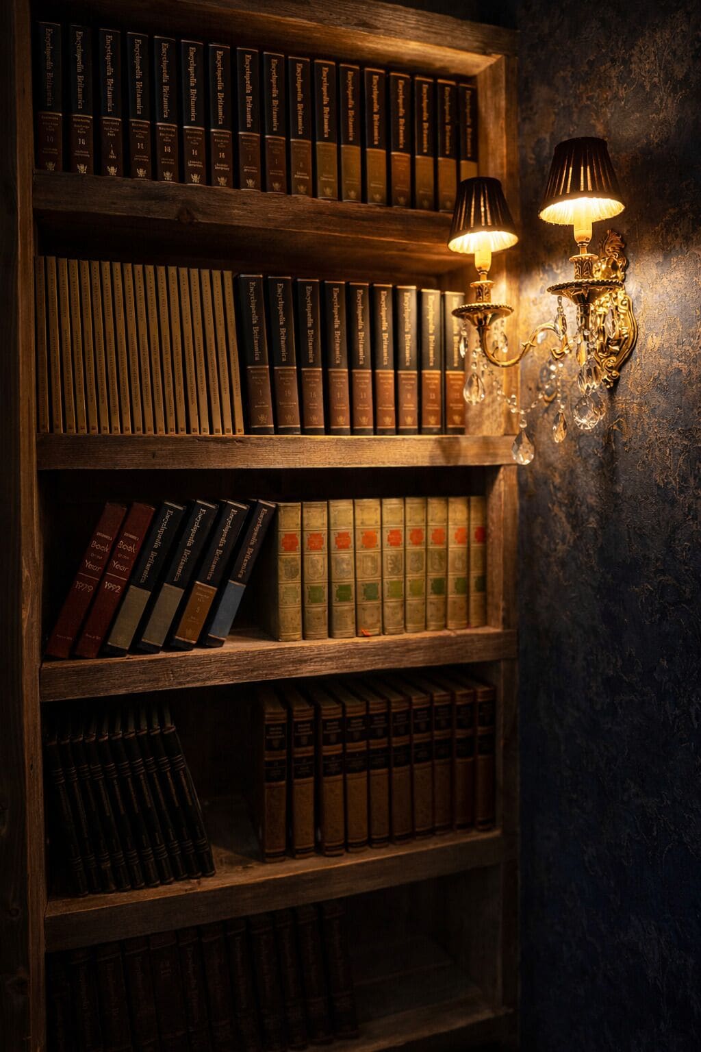 A bookshelf with books and two wall-mounted lamps.