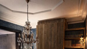 Un salon chaleureux avec une cheminée, un lustre et une bibliothèque.